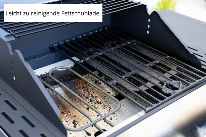 Nahaufnahme des Unold Barbecue Grill-Wagen Buddy zeigt fettige Roste, Rรผckstรคnde, sichtbares Heizelement und Grillteile. Auf einem deutschen Schild steht "Leicht zu reinigende Fettschublade".