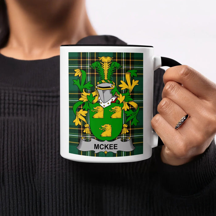 McKee family crest on a black and white mug held by a person.