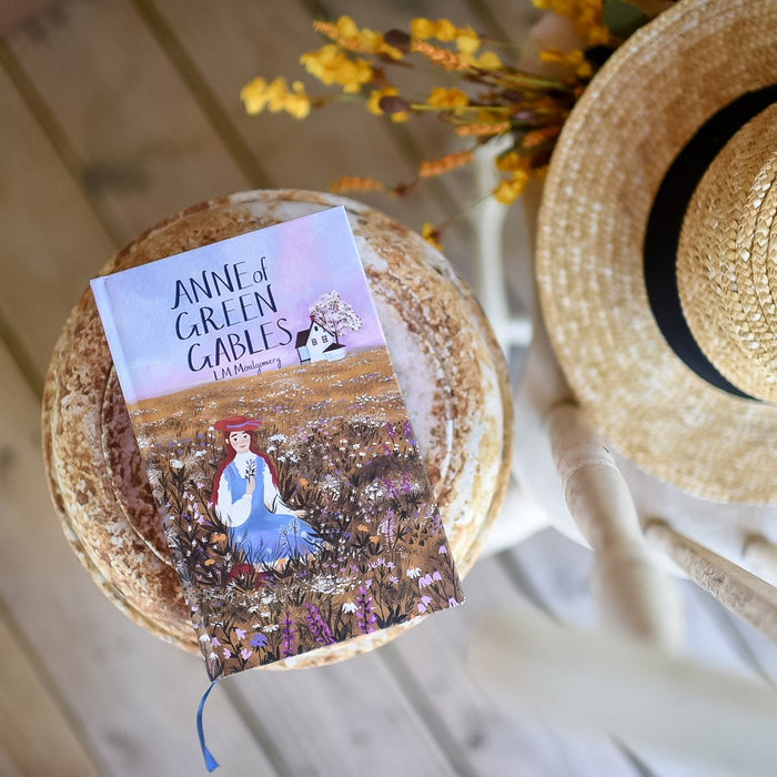 Anne Of Green Gables by L.M. Montgomery hardback book in purple with cover artwork of Anne. Slipcase has carrots, puff sleeves, and more!