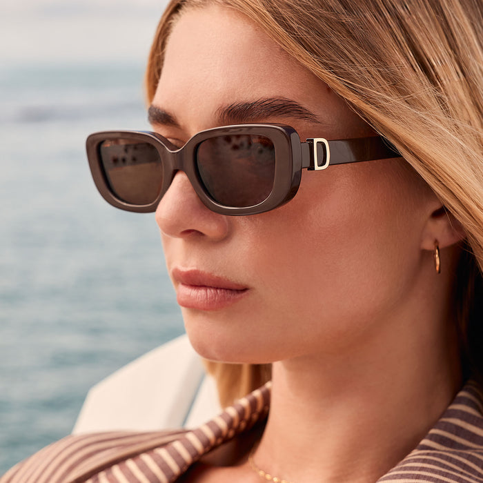lifestyle - female at the beach wearing diff eyewear featuring the daphne rectangle sunglasses with a truffle frame and truffle polarized lenses angled view