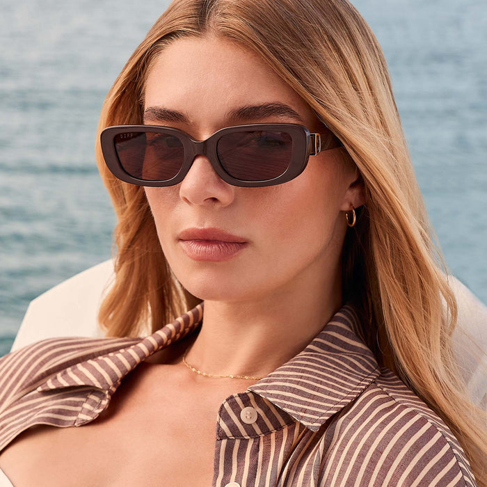 lifestyle - female at the beach wearing diff eyewear featuring the daphne rectangle sunglasses with a truffle frame and truffle polarized lenses front view