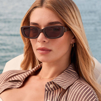 lifestyle - female at the beach wearing diff eyewear featuring the daphne rectangle sunglasses with a truffle frame and truffle polarized lenses front view
