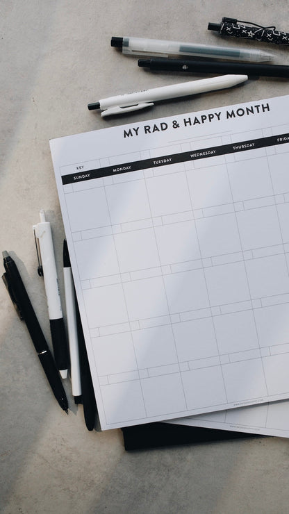 Month notepad with grid layout and pen on a gray surface