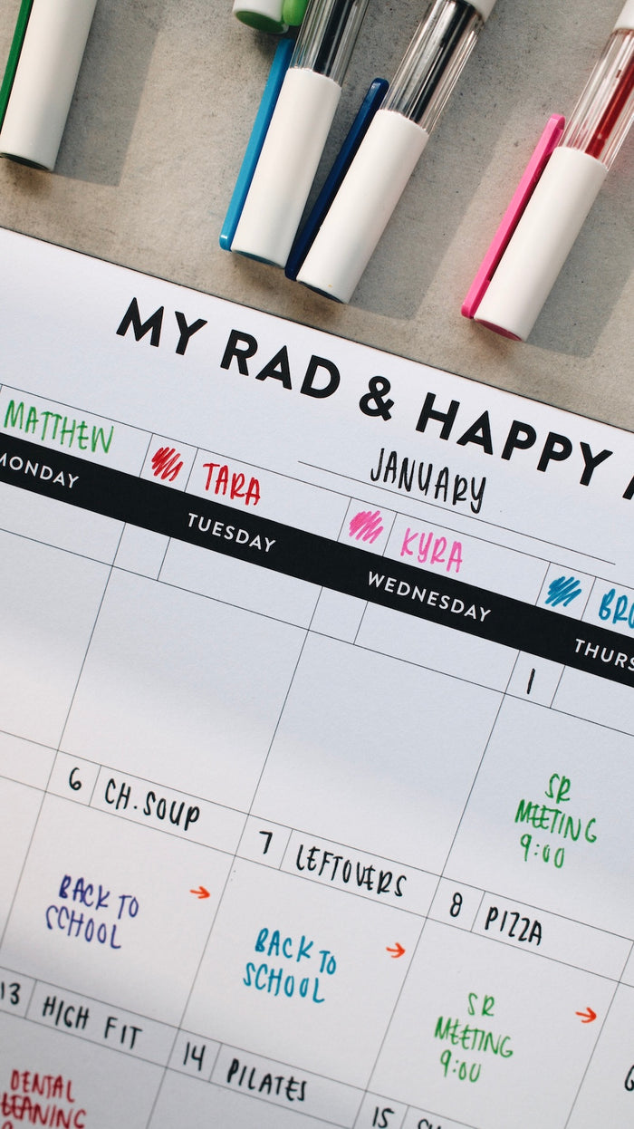 Month notepad with handwritten notes and markers on a desk