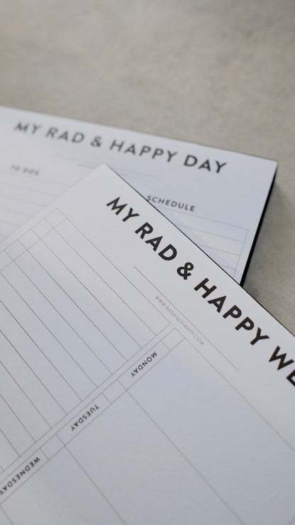 Two notepads with 'My Rad & Happy' branding on a light surface.