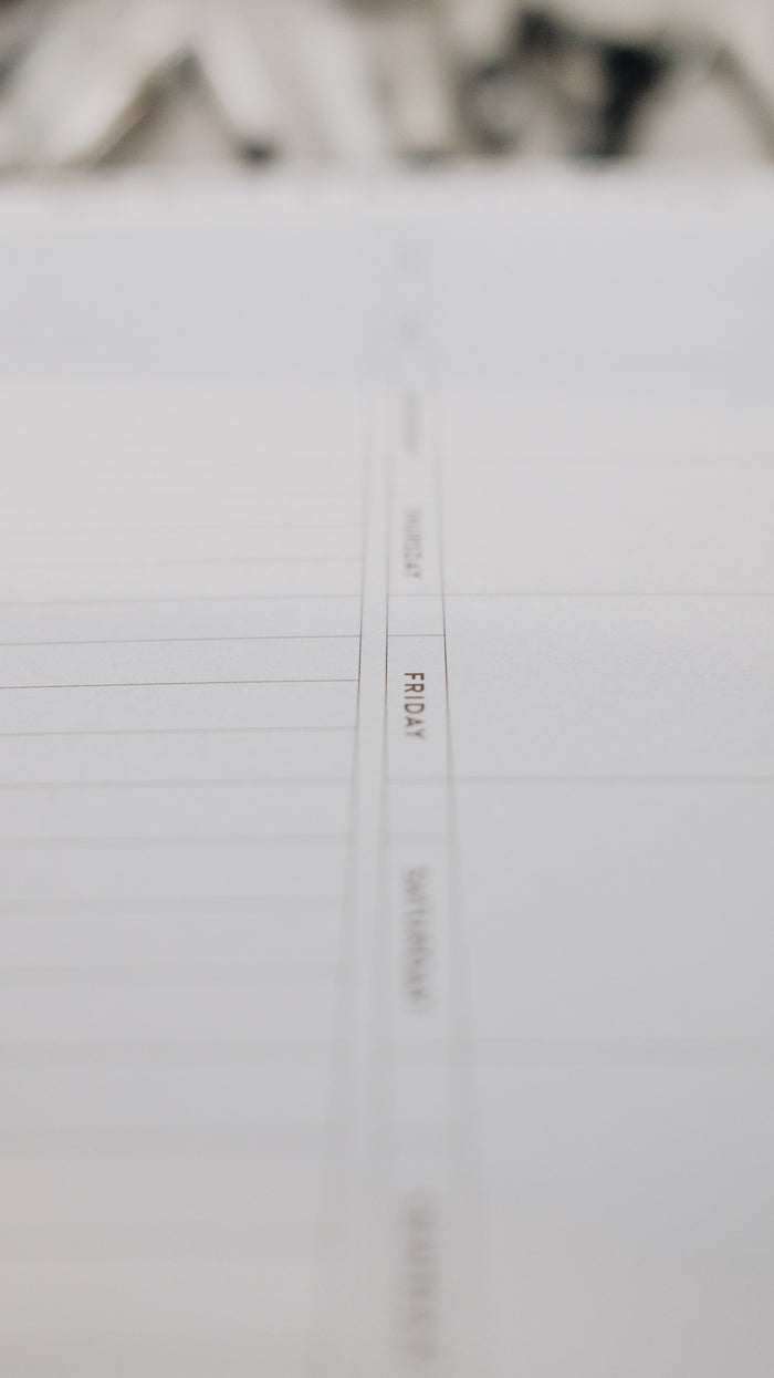 Close-up of a note pad focused on text 'FRIDAY' with blurred background.