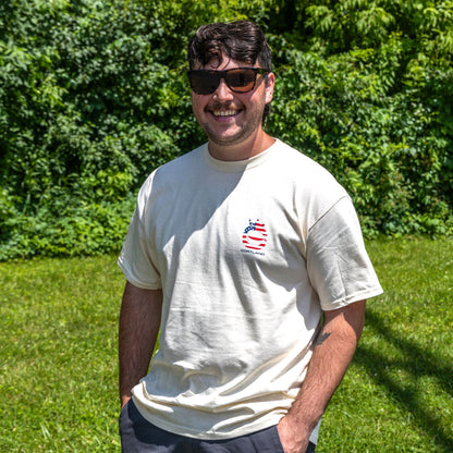 Man wearing sunglasses and a t-shirt with Cortland Line logo, standing in a grassy area with trees in the background.
