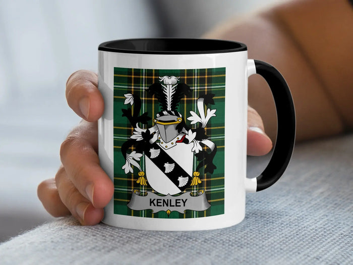 White mug with black rim featuring Kenley family crest on green plaid background.
