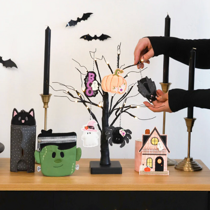 Person decorating a Halloween-themed table with various small decorative items.