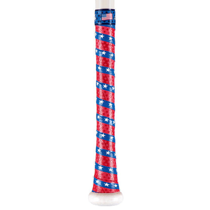 The handle of a baseball bat is wrapped with a Lizard Skins Specialty 1.1mm Durasoft Polymer Bat Grip in red, white, and blue with stars and diagonal stripes, finished with a small American flag sticker near the top.