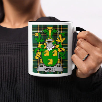 McKee family crest on a black and white mug held by a person.