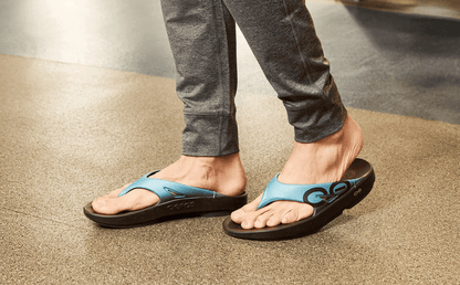 Person wearing blue sandals on a neutral background