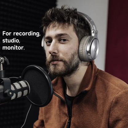 Man wearing headphones speaking into a microphone in a recording studio setting.
