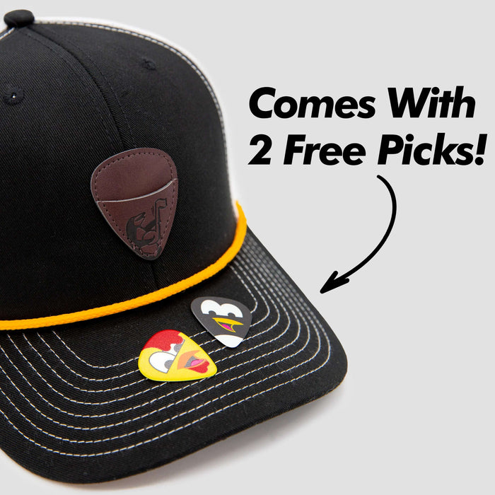 A black baseball cap with white stitching and a brown guitar pick holder is shown. Two colorful guitar picks rest on the brim. Text reads: Comes With 2 Free Picks! with an arrow pointing to the picks.