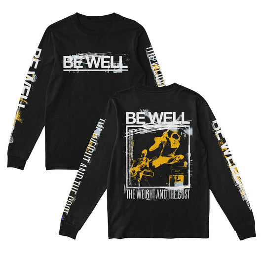 Be Well black long sleeve tee featuring BE WELL text on the front and sleeves. The back shows a yellow-tinted concert photo with BE WELL above and THE WEIGHT AND THE COST below.