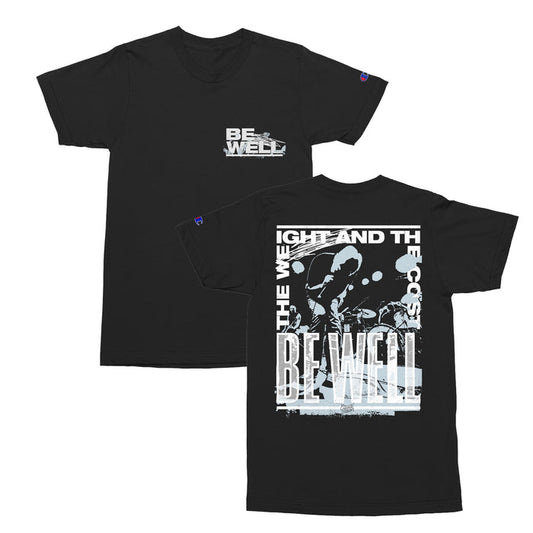 Be Well Coast T-Shirt in Black features BE WELL text on the front left chest; the back showcases a bold BE WELL print over a high-contrast band photo, framed by white text for a striking, iconic look.