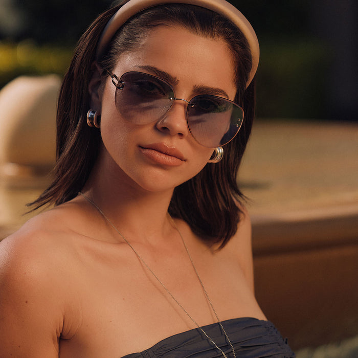 lifestyle - female sitting at a resturant wearing diff eyewear featuring the trista aviator sunglasses with a gold frame and slate blue gradient flash lenses front view