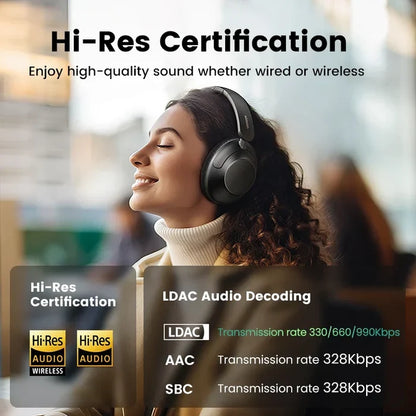 Wireless over-ear headphones worn by a woman with curly hair.