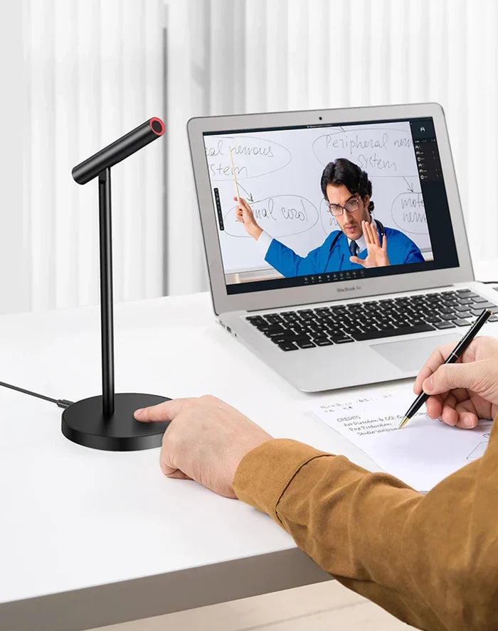 Laptop displaying a video conference call with a person gesturing on screen.
