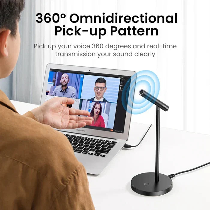Microphone with a circular base and adjustable stand positioned next to a laptop displaying a video call.